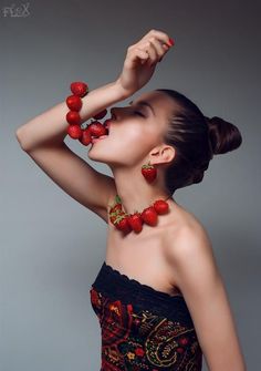 a woman in a strapless dress with strawberries on her neck and hands behind her head