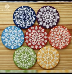 four different colored coasters sitting on top of a wooden table