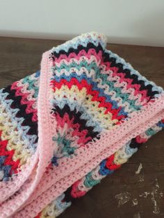 two crocheted blankets sitting on top of a wooden table