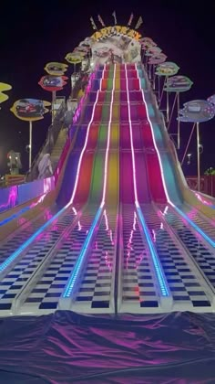 an illuminated carnival ride at night with umbrellas on the top and lights all around