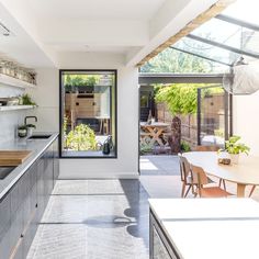 an open kitchen and dining area with glass doors leading to the back yard, covered in greenery