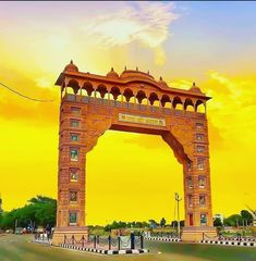 an arch in the middle of a road with people walking on it and yellow sky