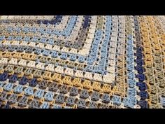 a crocheted blanket is laying on top of a tablecloth with blue, yellow and white squares