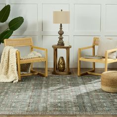 a living room with two chairs and a rug on the floor next to a lamp