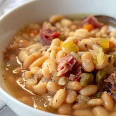 a white bowl filled with beans and ham