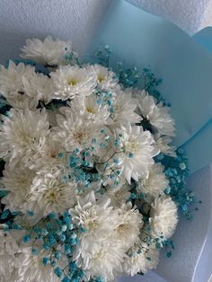 a bouquet of white and blue flowers in a paper wrapper on top of a table