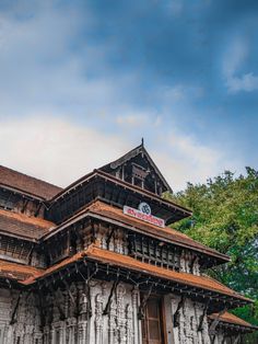 an old wooden building with a clock on it's side and trees in the background