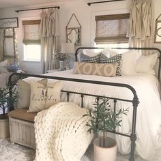 a bedroom with white bedding, pillows and plants on the side of the bed