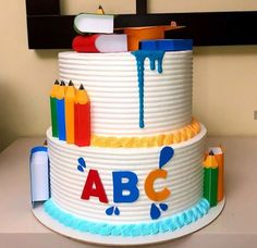 a three tiered cake decorated with crayons and the word abc on it