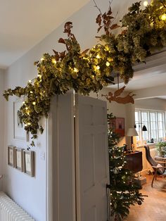 a refrigerator covered in christmas lights next to a wall with greenery growing on it