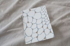 a piece of paper sitting on top of a bed covered in white and blue sheets