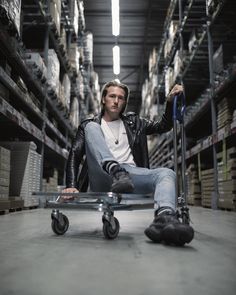 a man sitting on top of a skateboard in a warehouse