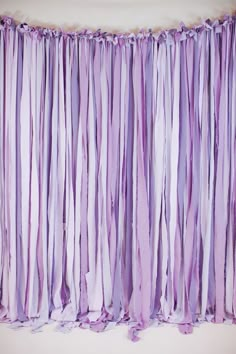 a purple curtain with fringes hanging from it's side on a white wall