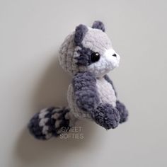 a crocheted stuffed raccoon is hanging on the wall with it's tail