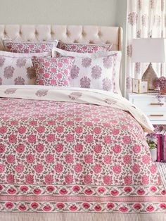 a bed with pink and white bedspread, pillows and blankets on top of it