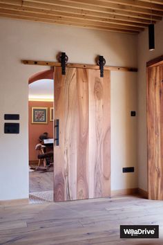 an open wooden door in the middle of a room with wood flooring and exposed beams