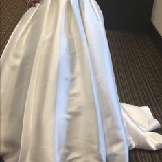 a woman in a white wedding dress is standing on the floor with her arms behind her back