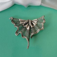 In an abstract triangular shape, this brooch/pendant was painstakingly handcrafted in silver. In a fan with curved folds a lattice was set, which is held at the edges with a curved border decorated with marcasites. With chain eyelet and pin clasp on the back, can be worn as a Brooch or a Pendant. Marked 925, maker not legible. Condition very good with age appropriate patina, circa 1930. Measures 2" across and 1.5" at longest length. Weighs 13.44g Comes in gift packaging. Silver Art Nouveau Jewelry For Evening, Handmade Silver Brooches For Evening, Silver Art Deco Filigree Brooches, Unique Silver Metal Brooch, Unique Silver Metal Brooches, Unique Silver Brooches For Evening, Art Deco Silver Brooch Jewelry, Art Nouveau Silver Brooch, Wedding Brooch