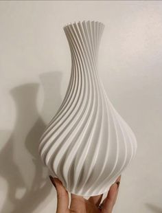 a hand holding a white vase with wavy lines on it's body and bottom