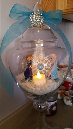 a christmas ornament in a glass bowl filled with snowflakes and figurines