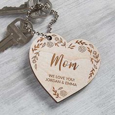 a wooden heart shaped keychain with the word mom engraved on it and two keys