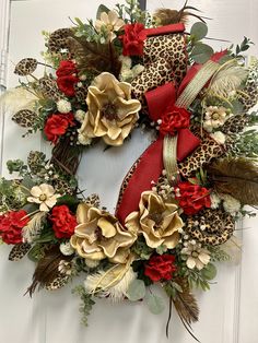 a leopard print wreath with red and gold flowers on the front door, decorated with ribbon