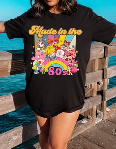 Step into a time machine of memories with our "Born in the 80s Nostalgia Retro Blast Tee." This vintage-inspired shirt is a vibrant tribute to the iconic era, featuring beloved characters like Strawberry Shortcake and her whimsical friends. Crafted from soft, comfortable fabric, this tee not only celebrates the spirit of the 80s but also offers a cozy fit for everyday wear. The lively design showcases a medley of colorful characters, bringing a burst of nostalgia to your wardrobe. Whether you're reliving your own 80s adventures or introducing the magic to a new generation, this tee is a perfect way to make a statement. Embrace the charm, fun, and enduring appeal of the 80s with every step you take in this delightful piece. Join us in celebrating the era that left an indelible mark on pop c Retro Character Print T-shirt For Fan Conventions, Vintage Crew Neck T-shirt With Cartoon Print, Retro T-shirt With Screen Print For Fan Conventions, Retro Graphic Print T-shirt For Fan Conventions, Vintage Cartoon Print Fan Merchandise T-shirt, Retro Crew Neck T-shirt With Character Print, Vintage Cartoon Print Fan T-shirt, Vintage Crew Neck T-shirt With Character Print, Retro Cartoon Print T-shirt For Fans