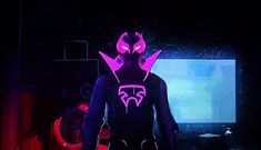 a person in a dark room wearing a neon pink mask and black hoodie with red eyes