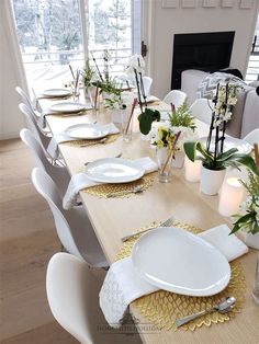 the table is set with white plates and silverware, flowers in vases and candles