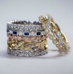 three different colored gold and silver rings with diamonds on top, one is blue and the other is white