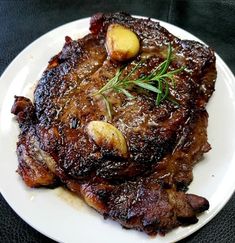 a white plate topped with meat and potatoes on top of a black tablecloth covered floor