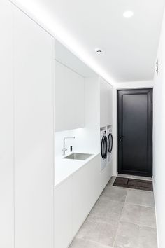 an empty laundry room with white walls and cabinets