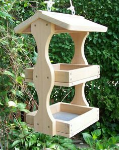 a wooden bird feeder hanging from a tree