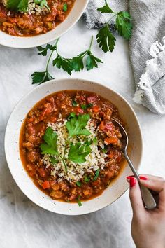 two bowls of chili with cheese and cilantro garnished with parsley