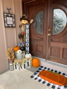 a welcome sign sitting next to a door with pumpkins and other decorations on it