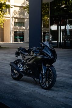 a black motorcycle parked in front of a tall building