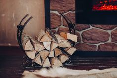 a pile of wood sitting on top of a wooden floor next to a fire place