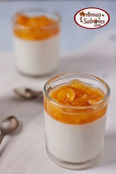 two small glass jars filled with food on top of a white tablecloth next to spoons