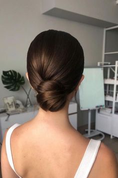 a woman with her back to the camera, wearing a white top and hair in a low bun