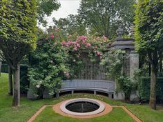 a circular bench in the middle of a garden with flowers growing on it's sides