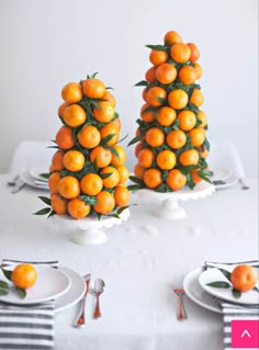 there are three oranges on the table with forks and knives in front of them