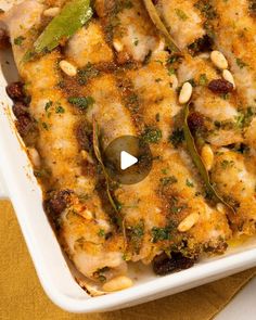 a casserole dish with chicken, pine nuts and green peppers in it on a yellow napkin