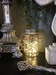 there is a mason jar with fairy lights in it next to some other items on the table