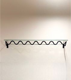 a glass shelf sitting on top of a white wall next to a black metal frame