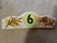 the number six is made out of felt and decorated with flowers, leaves and branches