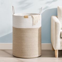 a white and beige basket sitting next to a couch in a room with blue walls