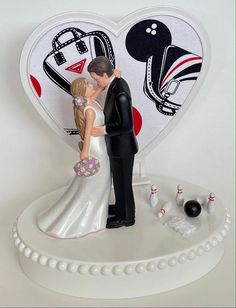 a wedding cake topper with a bride and groom kissing in front of a bowling alley