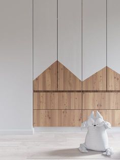 a white stuffed animal sitting on top of a hard wood floor next to wooden paneling