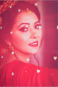 a woman with flowers in her hair and makeup looks at the camera while wearing a red dress