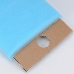 a piece of blue paper sitting on top of a cardboard box with a hole in it